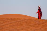 A woman carrying water for her animals through the Empty Quarter Desert in Oman.