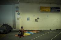 In greece, an Irani refugee pray  in the old Athens airport in the old departure terminal.