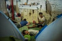 Refugees in the hone charging area by the tents in the old Athens airport in the old departure terminal in Greece