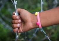 Afghani refugee girl is holding the racer-sharp wires of the fence to Hungary in her hand in the make-shift camp on the border crossing between the Hungarian and Serbian border in  Horgos, Serbia. 